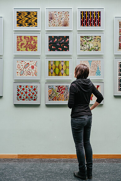 Student in front of a wall with historical patterns of cloth © HTW Berlin / Alexander Rentsch