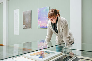 Studentin vor einer Glasvitrine mit Ausstellungsstücken