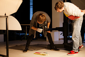 Zwei Studierende fotografieren im Fotostudio Ausstellungsobjekte