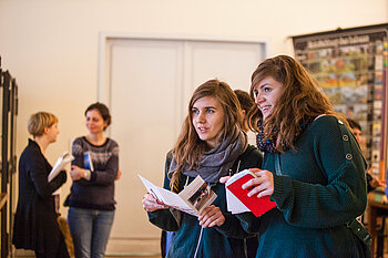 Zwei Studentinnen mit Flyern während einer Exkursion in einem Museum